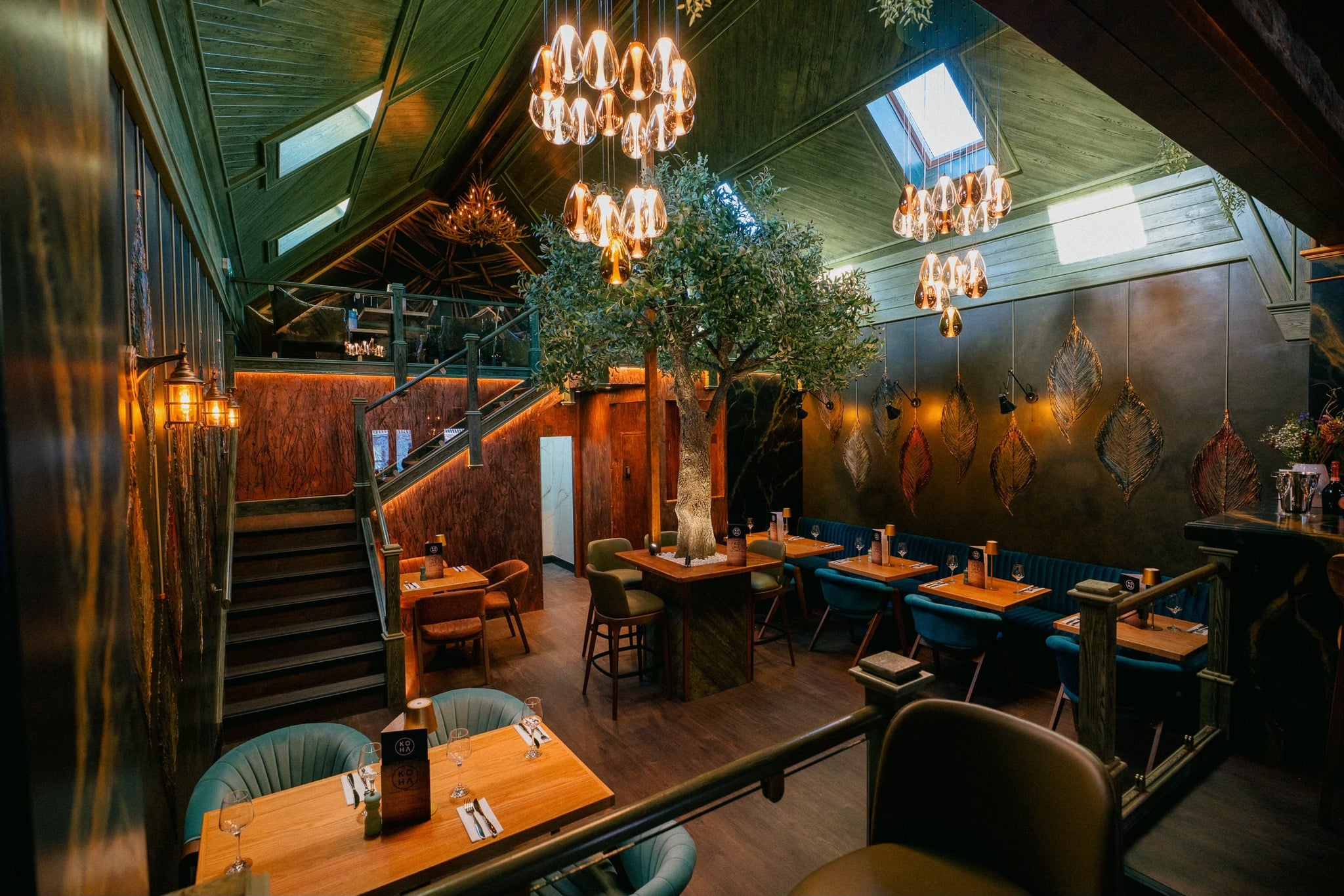KOHA restaurant interior with olive tree, teardrop chandeliers, and warm ambient lighting