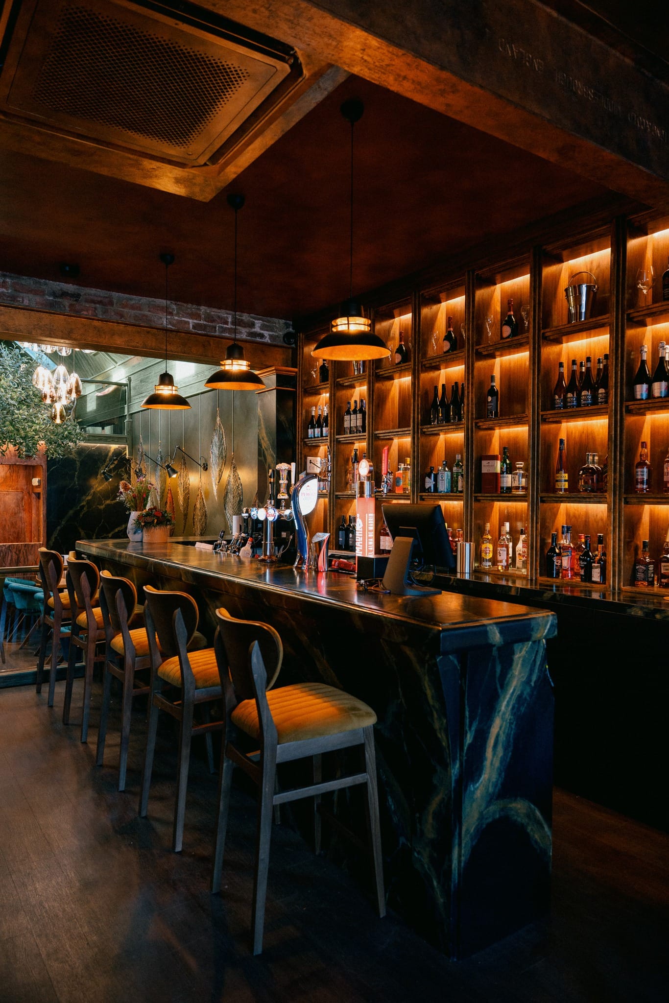 The elegant bar counter with backlit spirit shelves and marble finish